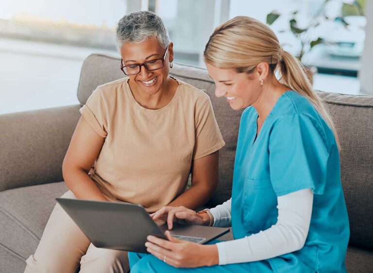 An older adult sitting with family and reviewing paperwork together at a kitchen table.