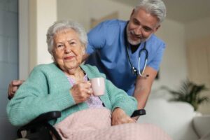 Staff guide assisted living residents through a hallway evacuation drill with emergency bags and mobility aids.